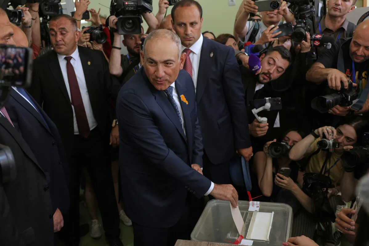 رئيس الوزراء الأرمني نيكول باشينيان يدلي بصوته في انتخابات برلمانية، محاطاً بالصحفيين والمراقبين، وسط أجواء من التوتر السياسي.