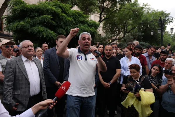 تجمع حشود من المتظاهرين في يريفان، حيث يتحدث أحد قادة المعارضة بلهجة حماسية، مع تواجد سياسيين آخرين خلفه، في سياق الاحتجاجات ضد الحكومة.