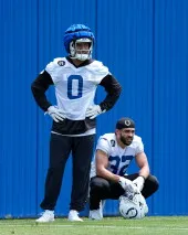 لاعب الدفاع Cam Bynum يرتدي زي فريق Indianapolis Colts خلال المعسكر التدريبي، مع زميله يجلس خلفه، في خلفية زرقاء.