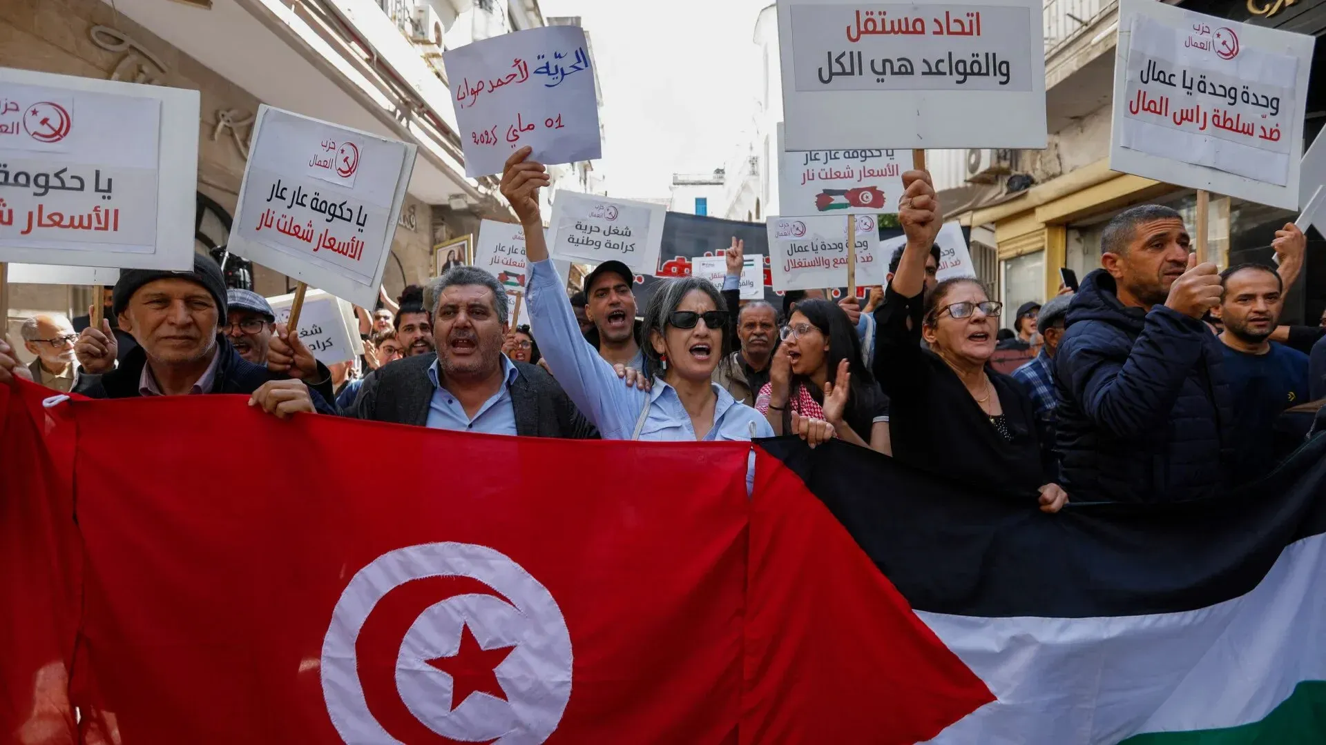 محتجون تونسيون يحملون لافتات ويهتفون ضد الحكومة، مع العلم الوطني التونسي في المقدمة، خلال مظاهرة تطالب بالعدالة والمساءلة.