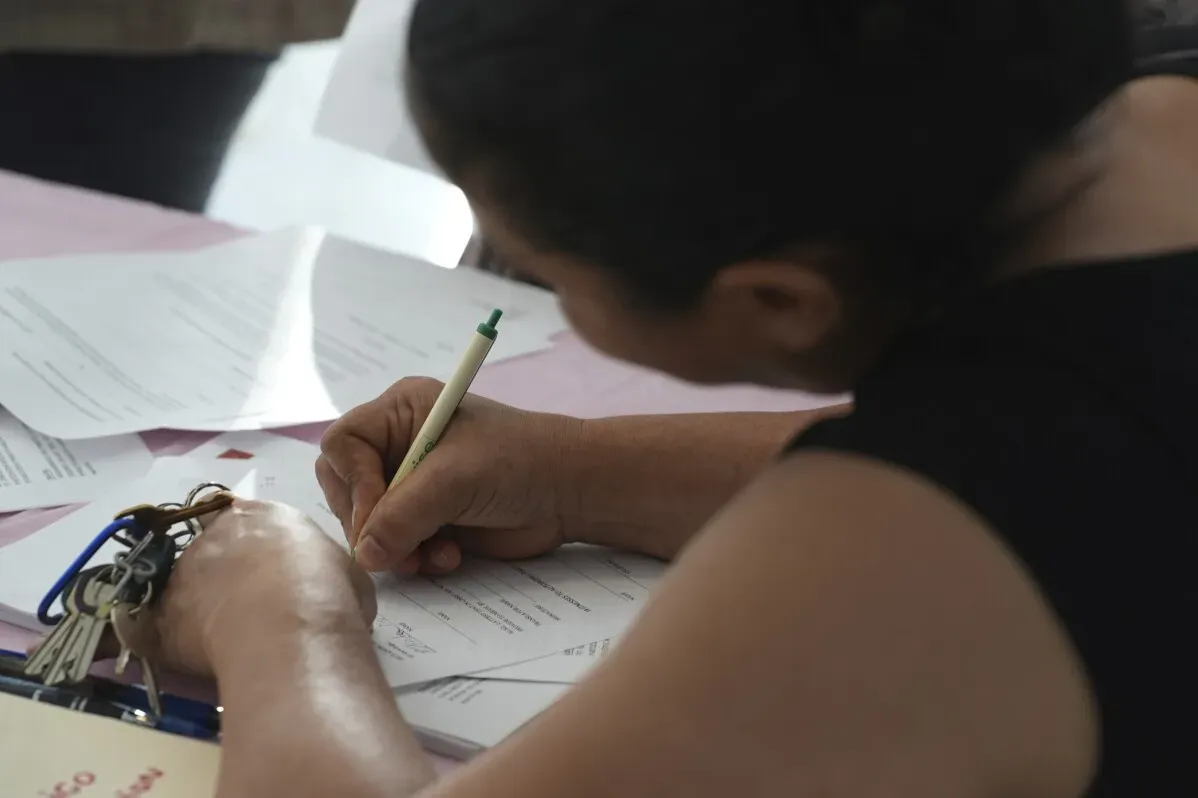 امرأة تكتب على ورقة بينما هي محاطة بوثائق مهمة، في اجتماع يركز على الاستعداد لعمليات الترحيل.