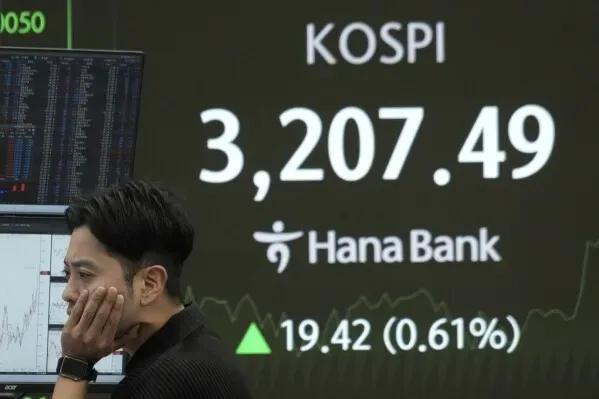 متداول ينظر بقلق إلى شاشة تعرض مؤشر كوسبي عند 3207.49، مع زيادة بنسبة 0.61%، في سياق تقلبات السوق الآسيوية.