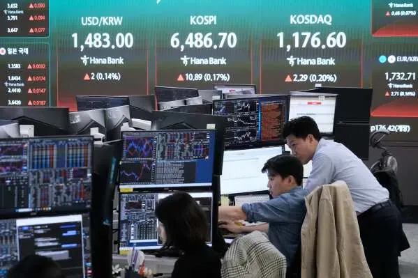 متداولون في غرفة تداول مع شاشات تعرض أسعار العملات ومؤشرات الأسهم، في سياق تباين أسواق الأسهم الآسيوية.