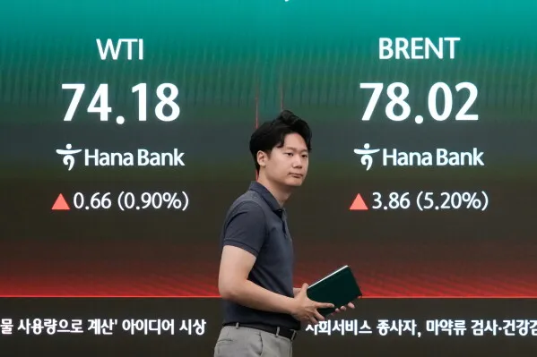 رجل يمشي أمام شاشة تعرض أسعار النفط الخام WTI وBrent مع ارتفاع ملحوظ في الأسعار وسط توترات الشرق الأوسط.