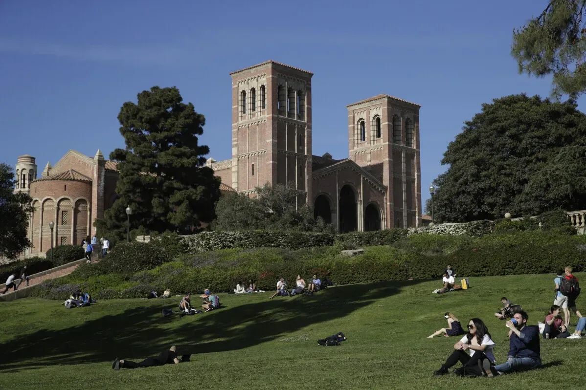 طلاب يجلسون على العشب أمام مبنى جامعي تاريخي، مما يعكس انخفاض تكاليف التعليم في الجامعات الحكومية الأمريكية.