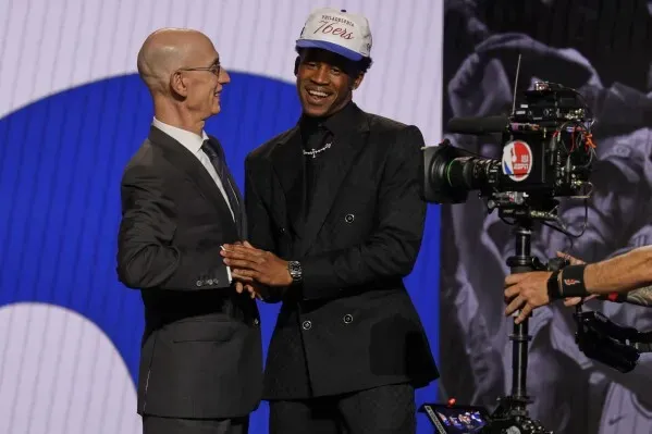 لاعب كرة السلة جي إدجكومب يرتدي قبعة فريق فيلادلفيا 76ers، يتصافح مع المفوض آدام سيلفر خلال حفل مسودة الدوري الأمريكي للمحترفين.