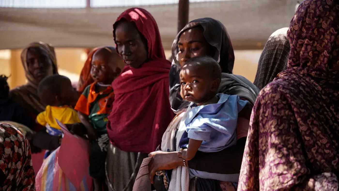 نساء وأطفال في الفاشر بالسودان ينتظرون الرعاية الصحية، وسط أزمة إنسانية بعد الهجمات على مستشفى الأمومة التعليمي.