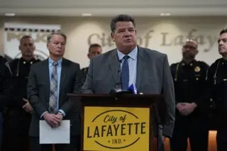 قائد شرطة لافاييت يتحدث في مؤتمر صحفي حول الهجوم على القاضي ستيفن ماير وزوجته، مع وجود ضباط خلفه.