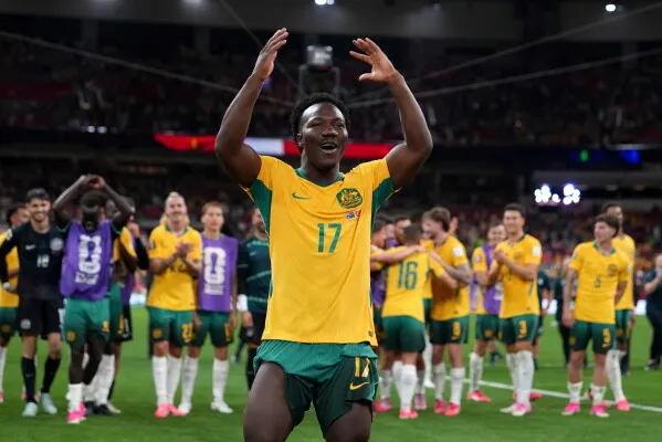 مابيل يحتفل بفوز منتخب أستراليا في كأس العالم، معبراً عن الفرح والتفاؤل، وسط زملائه في الفريق.