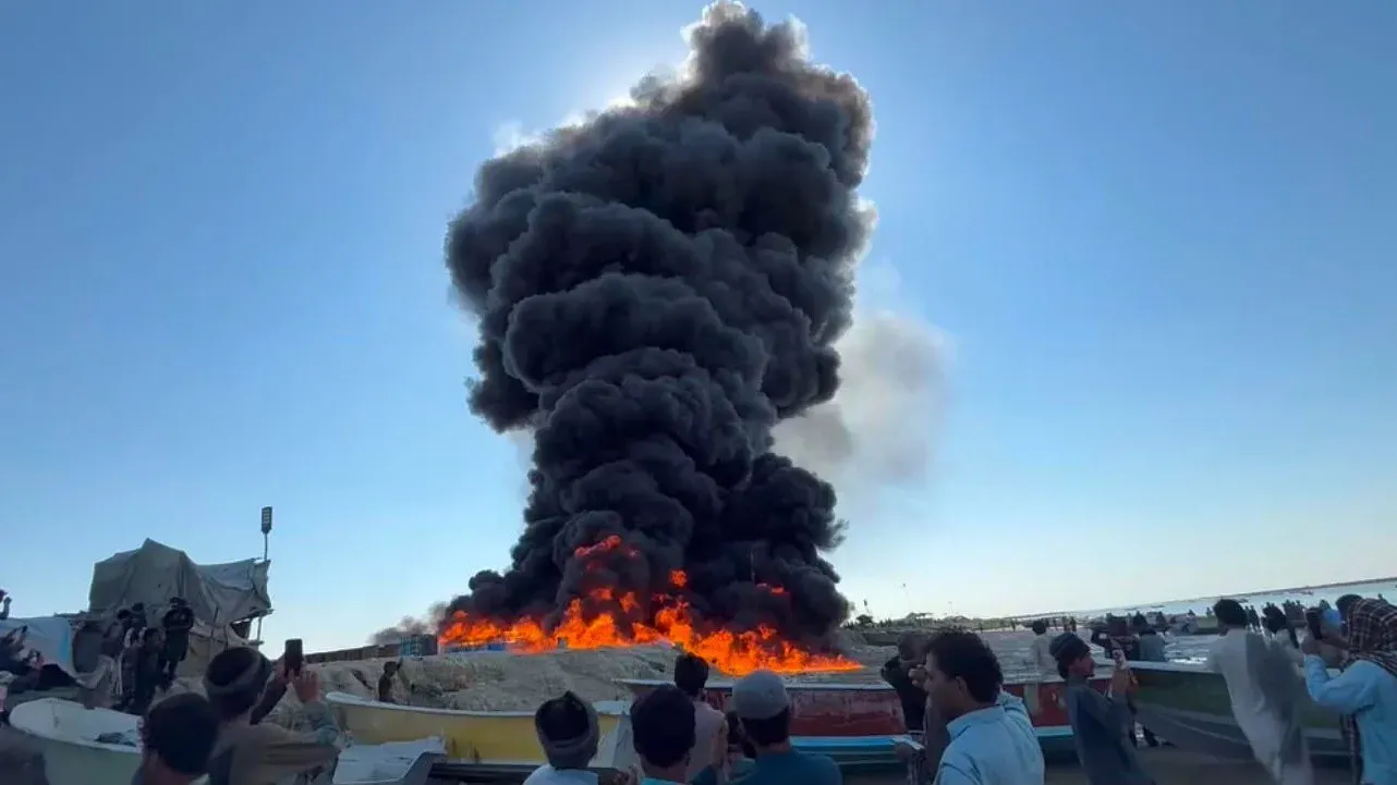 نيران كثيفة ودخان أسود يتصاعد من مستودع وقود محترق في كنتاني هور بإقليم بلوشستان، مع تجمع عدد من السكان المحليين يشاهدون الحريق.