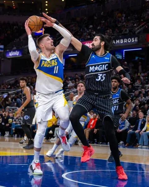 باولو بانشيرو يحاول صد تسديدة لاعب إنديانا بيسرز بينما يسعى فريق أورلاندو ماجيك لتحقيق الفوز في مباراة مثيرة.