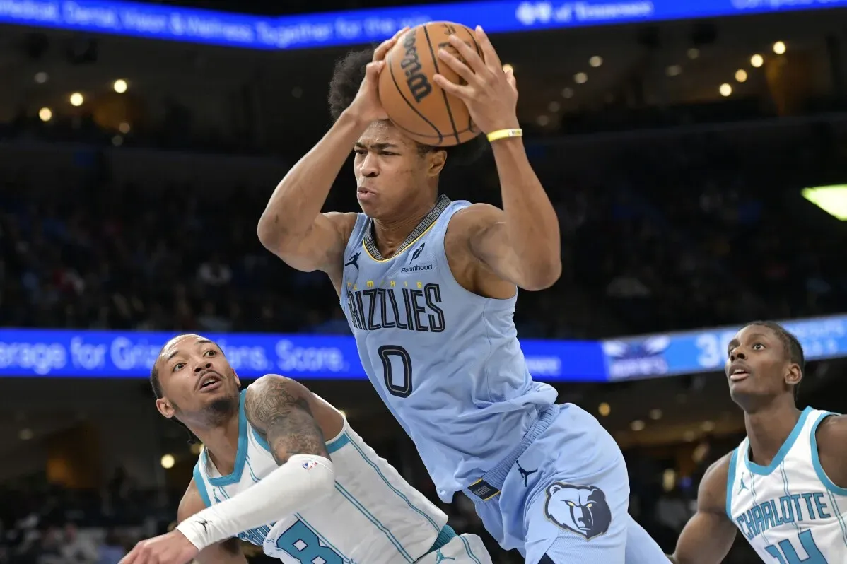 ديزموند بين لاعب ممفيس جريزليز يمسك الكرة أثناء المنافسة مع لاعبي شارلوت هورنتس في مباراة كرة السلة، مع تركيز على الأداء القوي لفريقه.