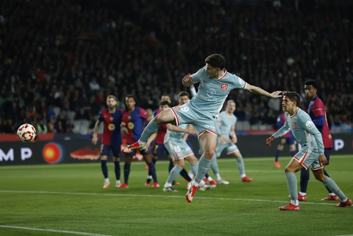 لاعب من أتلتيكو مدريد يقوم بتمريرة هوائية خلال مباراة مثيرة ضد برشلونة في نصف نهائي كأس الملك، حيث انتهت بالتعادل 4-4.