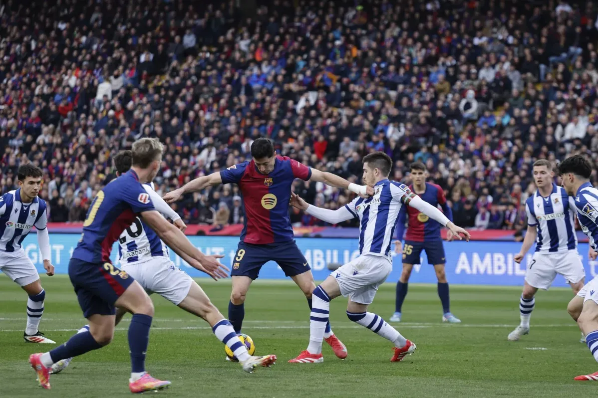 مباراة كرة قدم بين برشلونة وريال سوسيداد، حيث يواجه اللاعب ليفاندوفسكي مدافعي سوسيداد في أجواء حماسية.