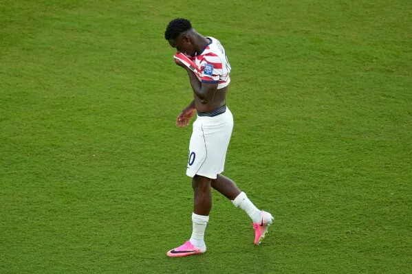 لاعب كرة القدم الأمريكي Folarin Balogun يمشي على أرض الملعب مرتدياً زي المنتخب الأمريكي، معبراً عن إحباطه خلال كأس العالم وسط جدل رفع إيقافه.