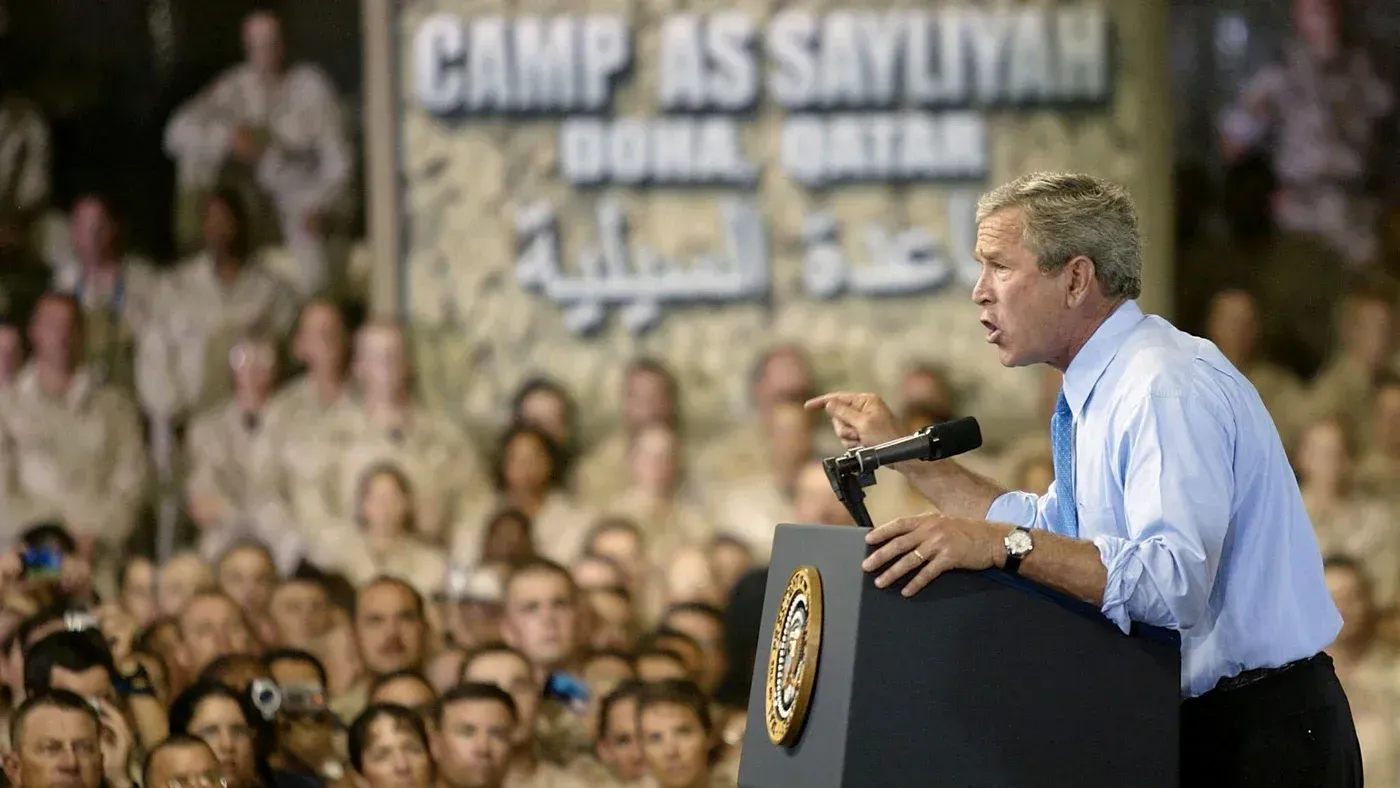 خطاب للرئيس الأمريكي جورج بوش في معسكر السيلية بقطر، حيث يتحدث أمام جنود في خلفية تحمل اسم المعسكر.