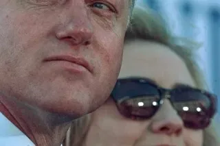 بيل وهيلاري كلينتون يبتسمان معًا في مناسبة عامة، مع التركيز على تعابير وجهيهما، مما يعكس شراكتهم السياسية المستمرة وسط التحديات.