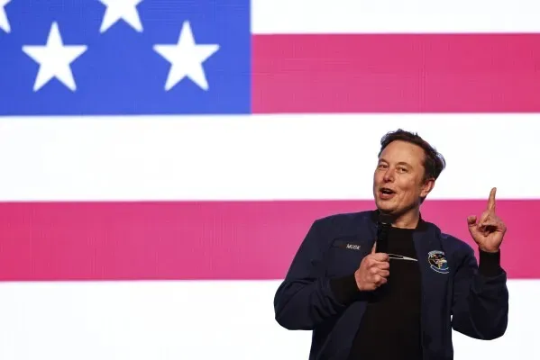 إيلون ماسك يتحدث أمام علم أمريكي، مع التركيز على تأثيره في سباق المحكمة العليا في ويسكونسن الذي شهد إنفاقًا قياسيًا.