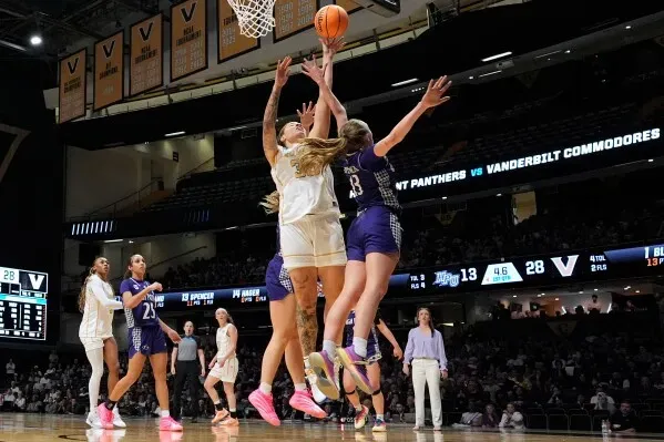 لاعبة كرة سلة من فريق فاندربيلت تسجل نقطة تحت ضغط من لاعبة من فريق هاي بوينت خلال مباراة NCAA.