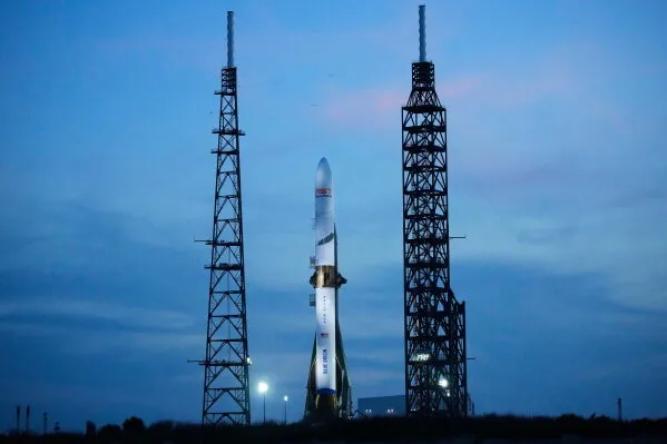 صاروخ New Glenn من شركة Blue Origin واقفاً على منصة الإطلاق في قاعدة Cape Canaveral، مع وجود برجين جانبيين، في أجواء غائمة.