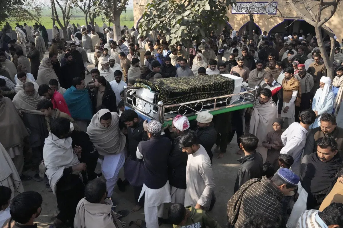 جمع حشد كبير من الناس في جنازة باكستانيين غرقوا أثناء محاولة الهجرة إلى أوروبا، حيث تُحمل الجثامين على النعوش.