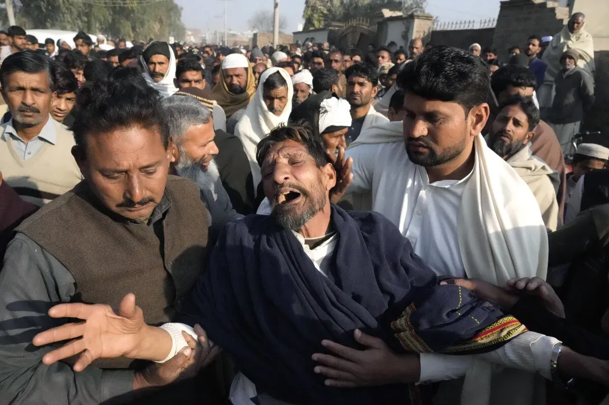 تجمع حشود من الناس في جنازة باكستانيين غرقوا أثناء محاولة الهجرة، مع ظهور مشاعر الحزن والأسى على وجوههم.