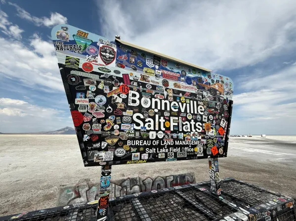 لوحة ملصقات ملونة كبيرة تحمل اسم Bonneville Salt Flats في سهل ملحي واسع في يوتا، موقع تسجيل أندي غرين للرقم القياسي في سرعة سيارات الهيدروجين.