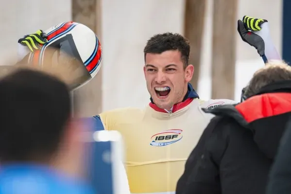 مات ويستون يحتفل بفوزه بلقب كأس العالم للتزلج الهيكلي للرجال في ألتنبرغ، ألمانيا، مع ارتداء خوذته.