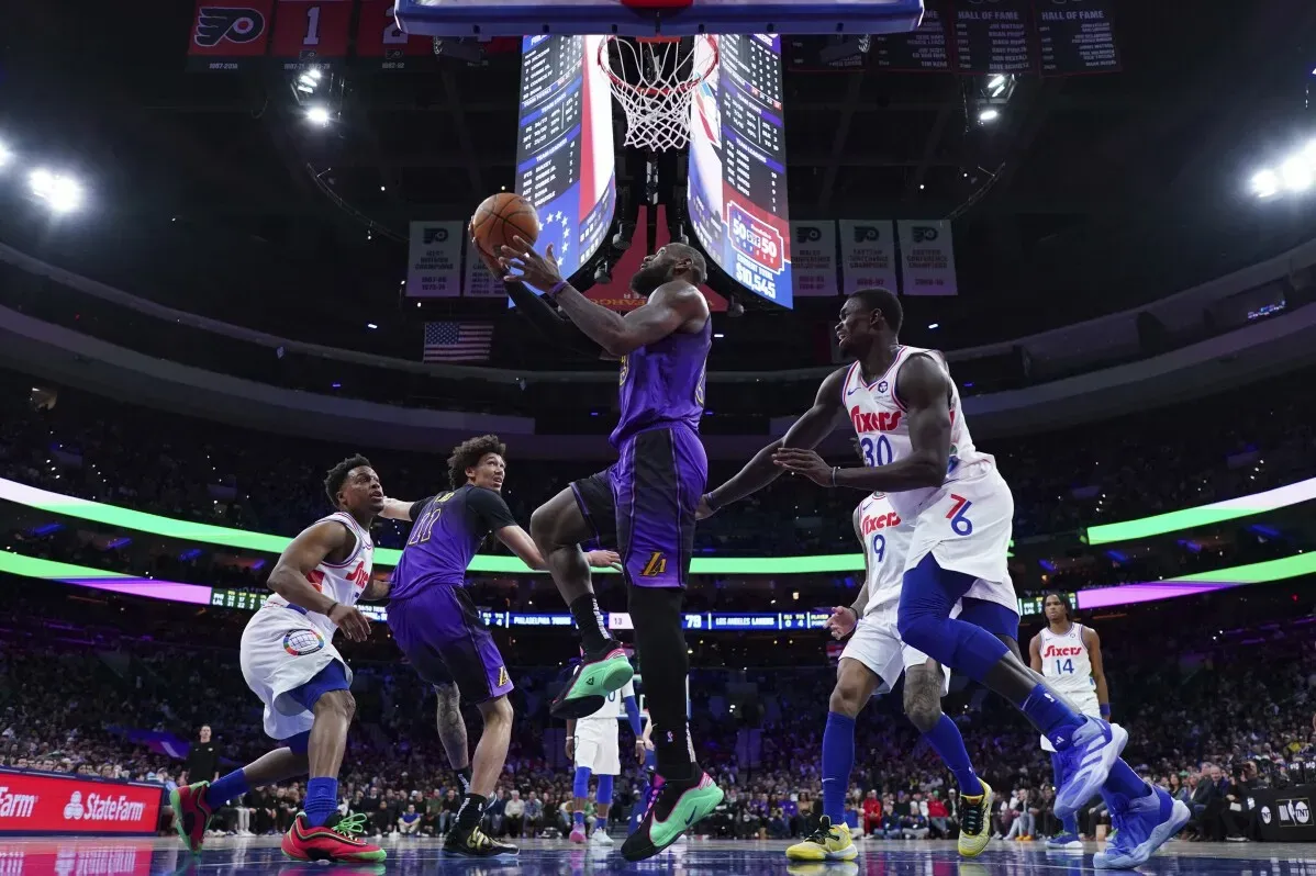 بروني جيمس يحاول التسجيل تحت سلة فريق 76ers في مباراة لوس أنجلوس ليكرز، ويظهر المنافسون في محاولة لعرقلته.