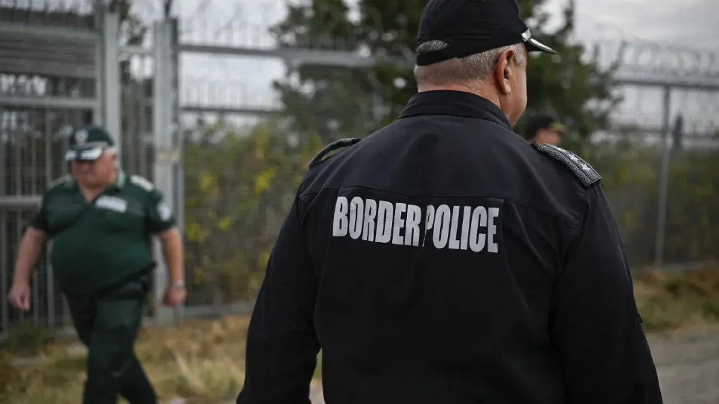 شرطي حدودي يتجول بالقرب من سياج حدودي، يعكس التوترات في عمليات إنقاذ المهاجرين على الحدود البلغارية.