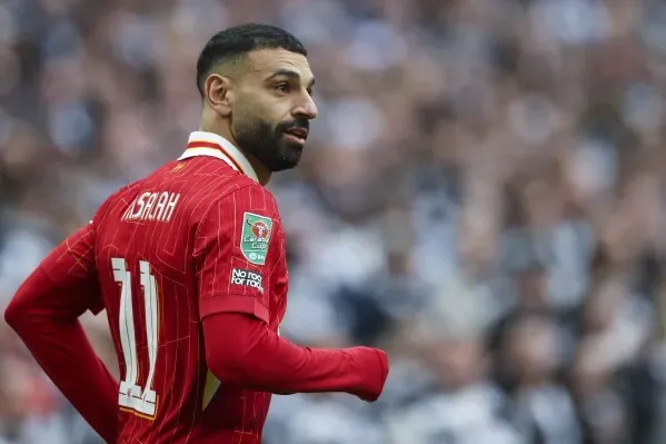 محمد صلاح، لاعب ليفربول، يرتدي القميص الأحمر رقم 11، في مباراة رسمية، مع تعبير جاد على وجهه، يعكس التزامه بالنادي.