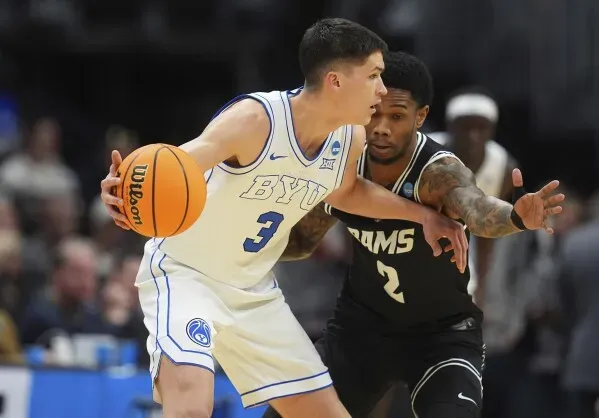 لاعب كرة سلة من فريق BYU يتجاوز مدافع فريق VCU، مع التركيز على الكرة خلال مباراة في بطولة NCAA.