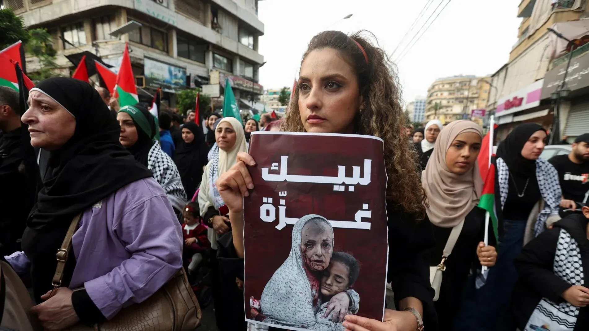 امرأة تحمل لافتة مكتوب عليها "ليتك غزّة" خلال مظاهرة في لبنان، حيث يتجمع المتظاهرون دعماً لفلسطين.