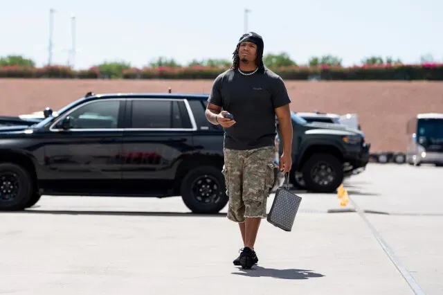 المدافع والتر نولين الثالث يسير نحو ملعب التدريب في أريزونا، مرتديًا ملابس غير رسمية ويحمل حقيبة، بينما يستعد للعودة من إصابة.