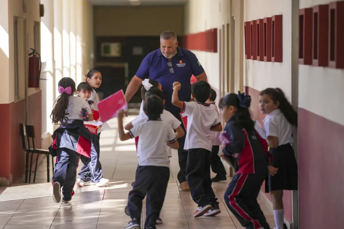 مدير مدرسة ابتدائية في كولياكان يتفاعل مع الطلاب في ممر المدرسة، وسط أجواء من القلق بسبب العنف المتزايد في المدينة.