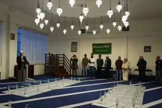 مسجد في ميلانو يستضيف إفطارًا جماعيًا خلال شهر رمضان، حيث يجتمع المصلون تحت المصابيح المعلقة لتناول الطعام والصلاة.