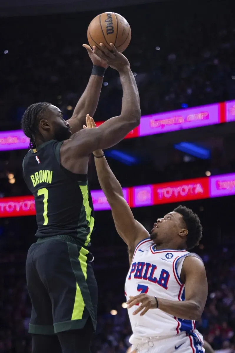 جايلين براون يسجل نقطة خلال مباراة سيلتيكس ضد 76ers، مع لاعب فيلادلفيا يحاول الدفاع عنه، في أجواء تنافسية حماسية.