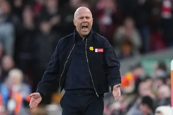 مدرب فريق كرة القدم يبدو متحمسًا أثناء توجيه تعليماته في مباراة حاسمة، مع تواجد الجماهير في الخلفية.