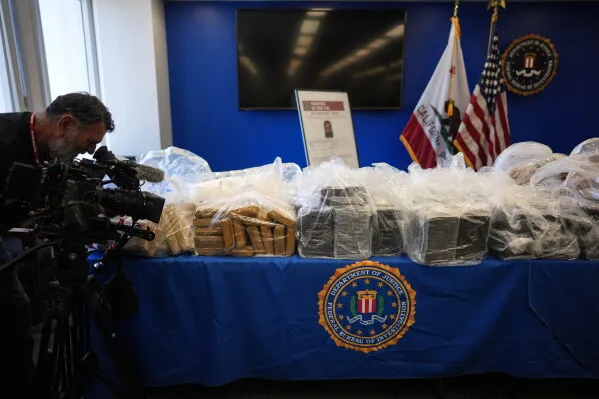 مضبوطات كبيرة من المخدرات وأسلحة معروضة خلال مؤتمر صحفي للـ FBI حول تفكيك شبكات إجرامية هندية دولية.