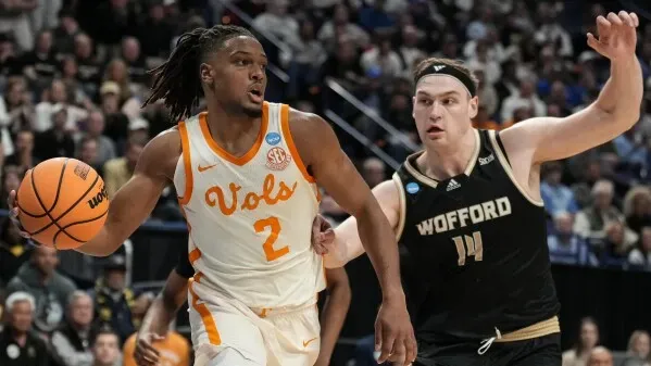 لاعب كرة سلة من فريق تينيسي يحمل الكرة ويتجاوز مدافعًا من فريق ولفورد خلال مباراة في بطولة NCAA.