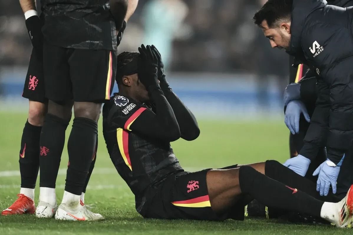 نوني مادويكي لاعب تشيلسي مصاب، يجلس على الأرض ويغطي وجهه بيديه بينما يتلقى المساعدة من الطاقم الطبي.