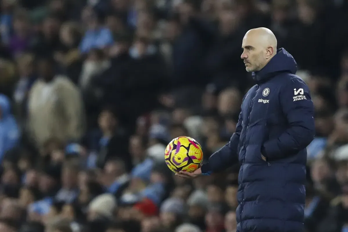 مدرب تشيلسي يحمل كرة قدم أثناء مباراة، مع وجود جمهور في الخلفية، في سياق دوري أبطال أوروبا.