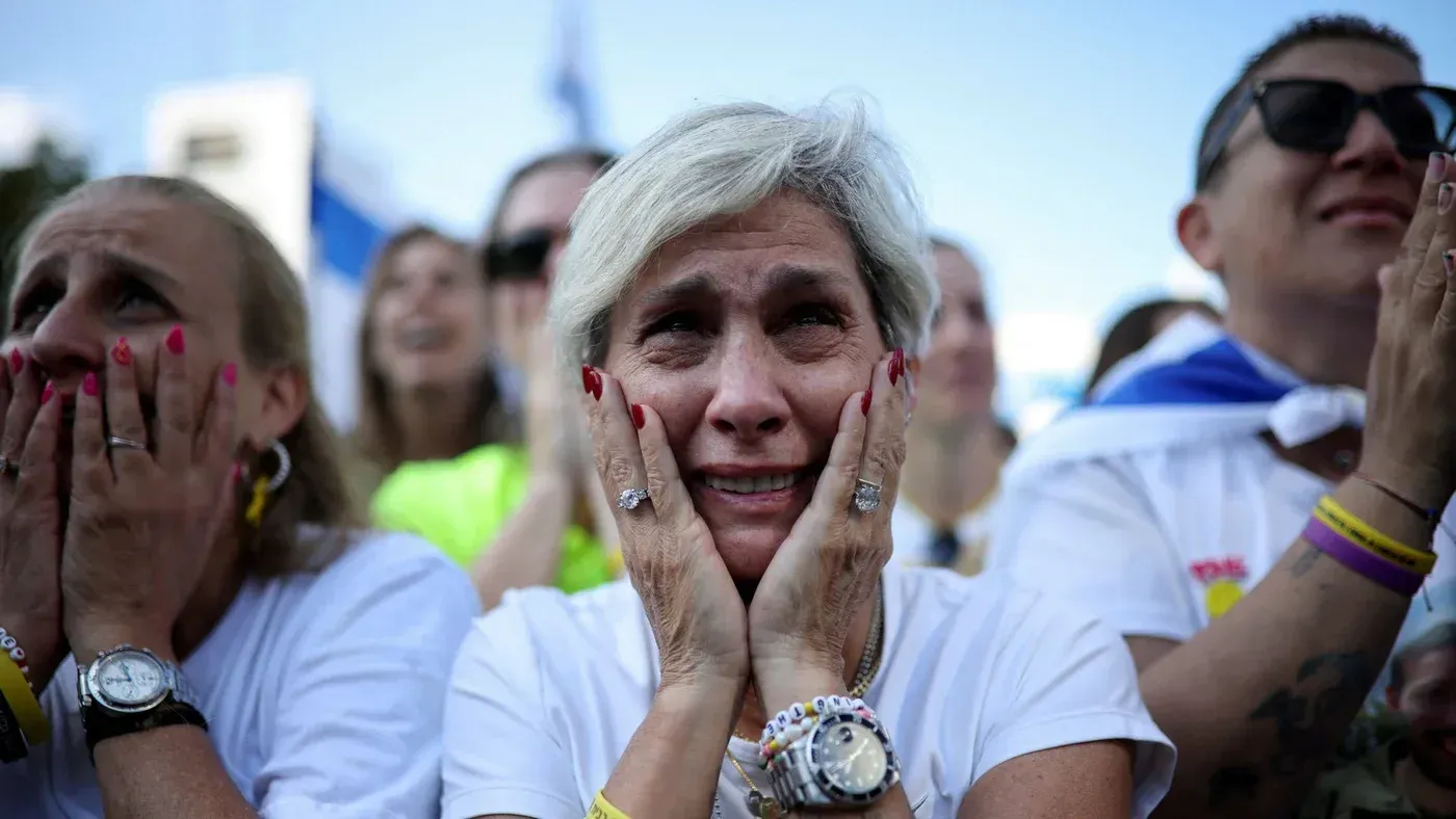 نساء ورجال في ساحة تل أبيب يعبرون عن مشاعر الفرح والقلق أثناء انتظارهم أخبار الإفراج عن الأسرى الإسرائيليين.