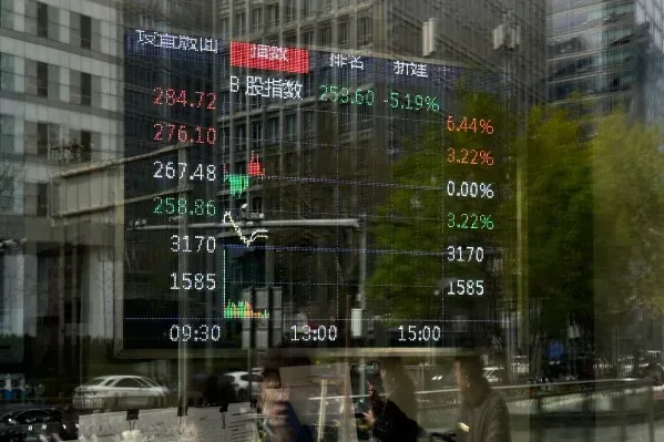 شاشة عرض تظهر بيانات سوق الأسهم في بكين، مع ارتفاع وانخفاض المؤشرات، تعكس تأثير التعريفات الجمركية الأمريكية على الاقتصاد.