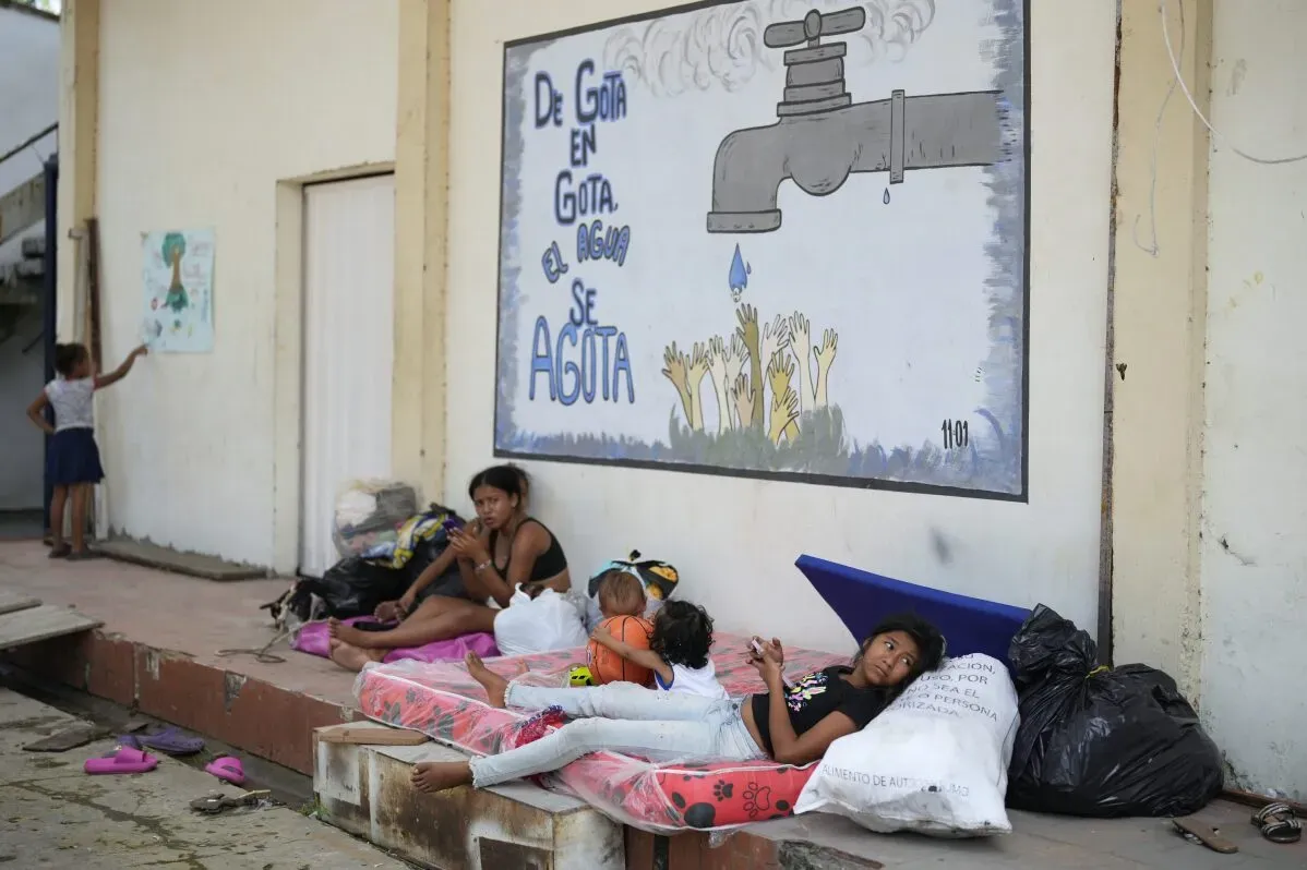 عائلة نازحة تستقر في مكان مؤقت مع طفلين، بينما تعبر جدارية عن نقص المياه في كولومبيا، وسط أزمة العنف والنزوح.