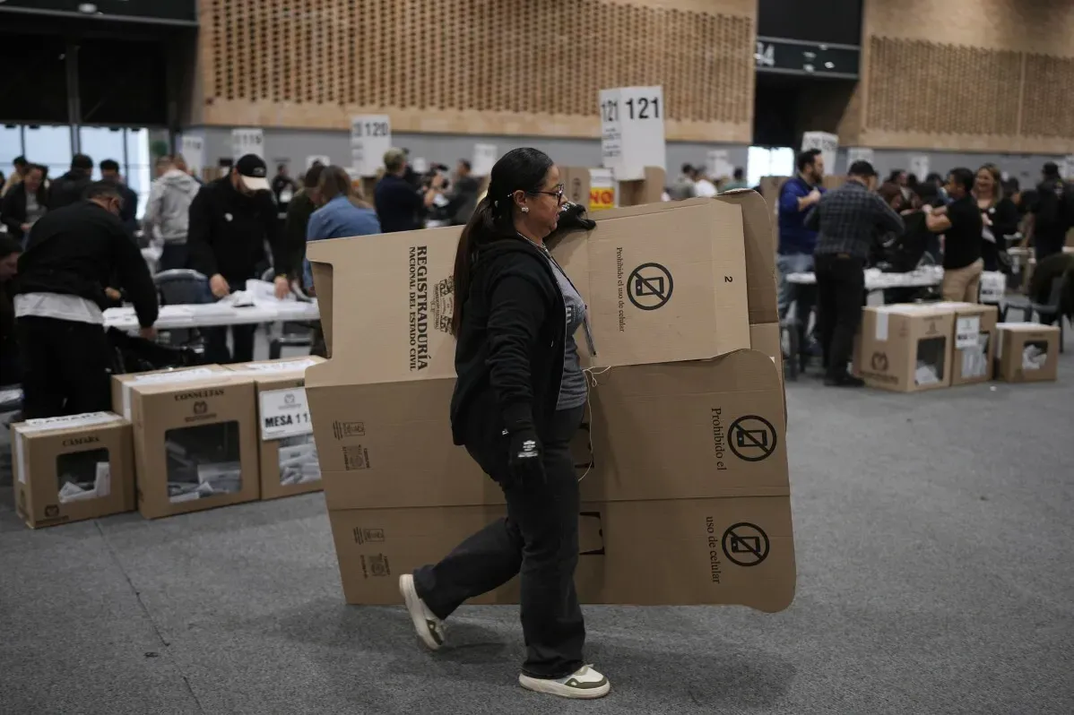 امرأة تحمل صناديق كبيرة في مركز فرز الأصوات ببوغوتا، حيث يتجمع المشاركون بعد انتخابات الكونغرس الكولومبية.