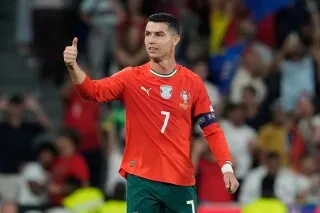 رونالدو يرتدي قميص المنتخب البرتغالي، يظهر وهو يرفع إبهامه بإيجابية، في مباراة دولية، مع خلفية جماهيرية حماسية.
