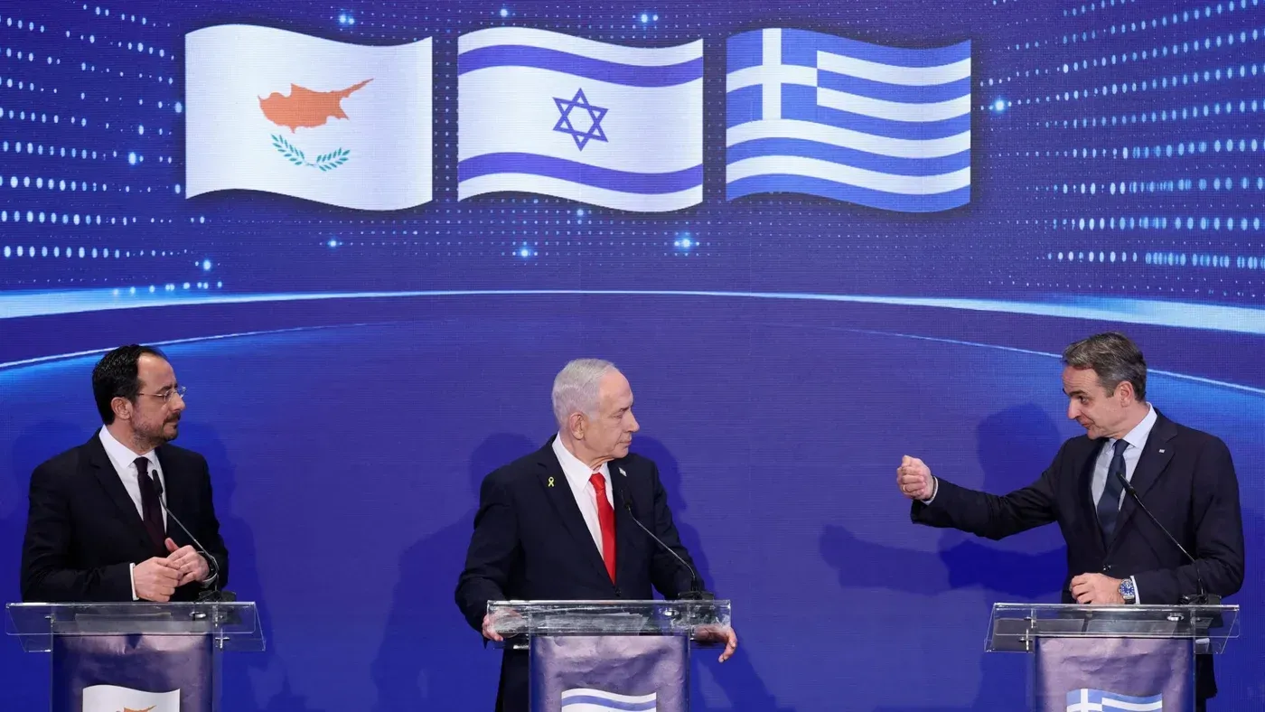 اجتماع ثلاثي بين قادة قبرص وإسرائيل واليونان، مع أعلام الدول خلفهم، يناقش التوترات الإقليمية.