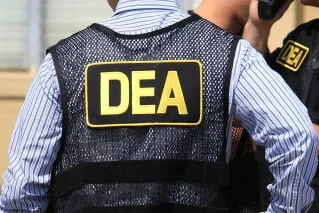 موظف يرتدي سترة تحمل شعار وكالة مكافحة المخدرات الأمريكية DEA، في سياق التحقيقات حول سياسة مراقبة شحنات الفنتانيل دون مصادرتها.
