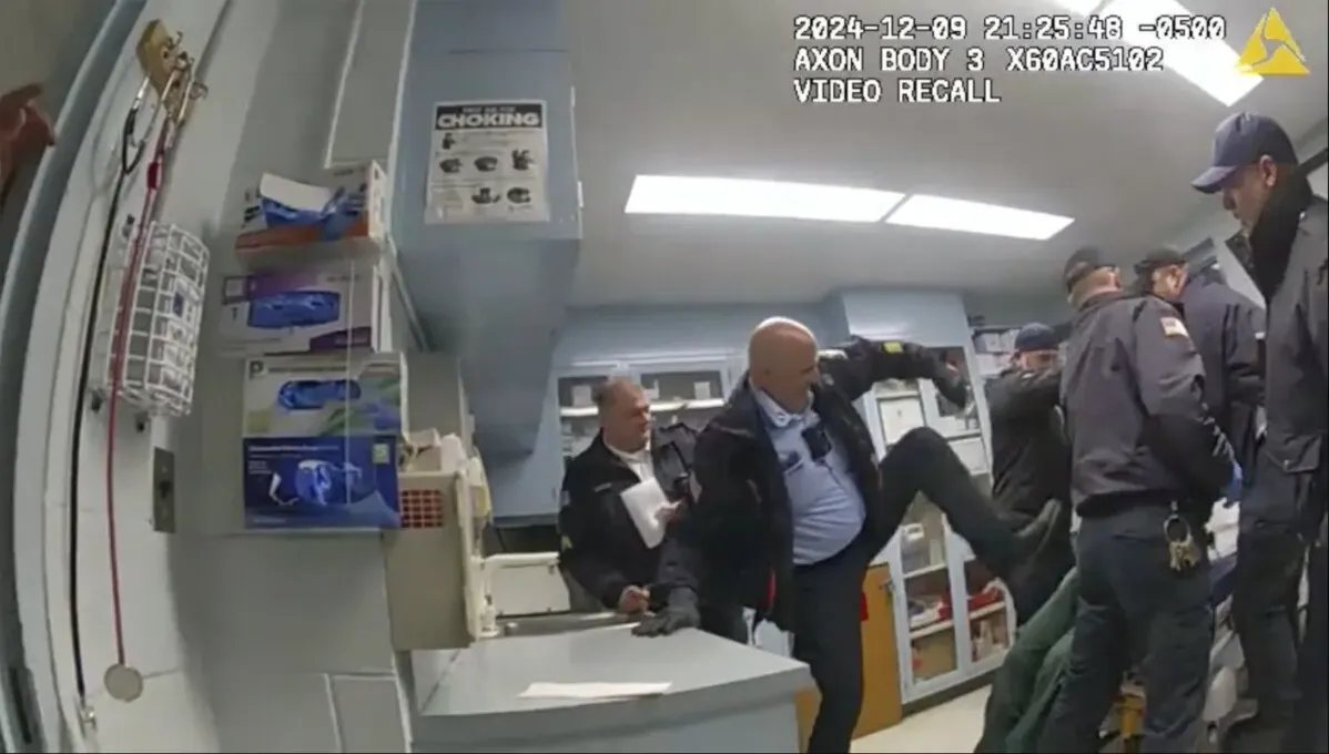 اعتداء عنيف على رجل مكبل اليدين من قبل ضباط الإصلاحيات في غرفة طبية، مما أدى إلى وفاته. تُظهر الصورة مشهد الاعتداء.